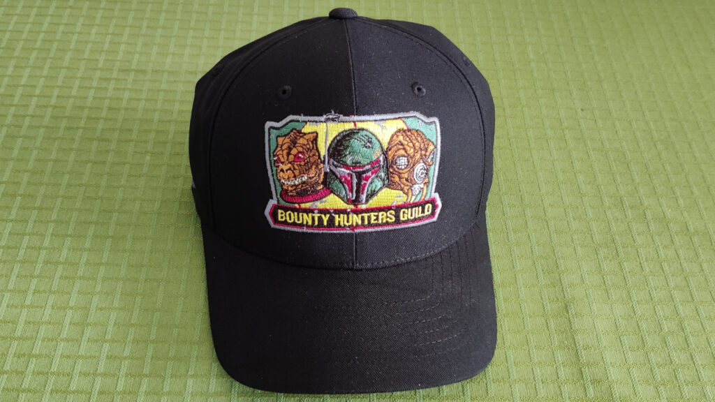 Front view of the hat. The faces/helmets of three bounty hunters and "Bounty hunters guild" is embroidered on the front.