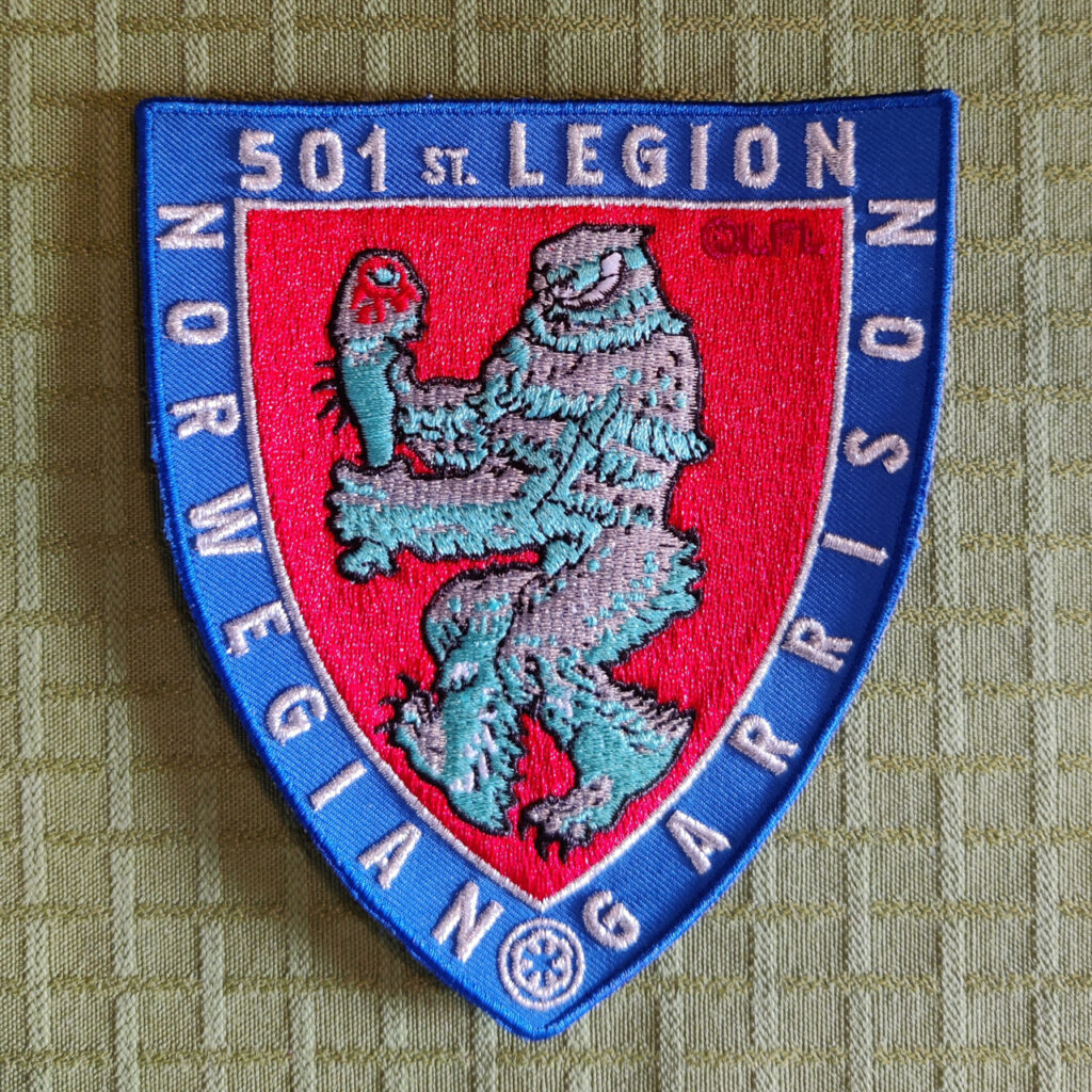 A embroidered patch in the shape of a shield. It's the same as the regular patch, but all white threads is silver instead.