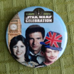 A button with a family picture style photo montage of 1990s Carrie Fisher, Harrison Ford and Adam Driver. Driver is wearing a souvernir Union Jack felt hat. Big Ben is towering in the background. The Star Wars Celebration Europe 2023 logo is at the top of the button.