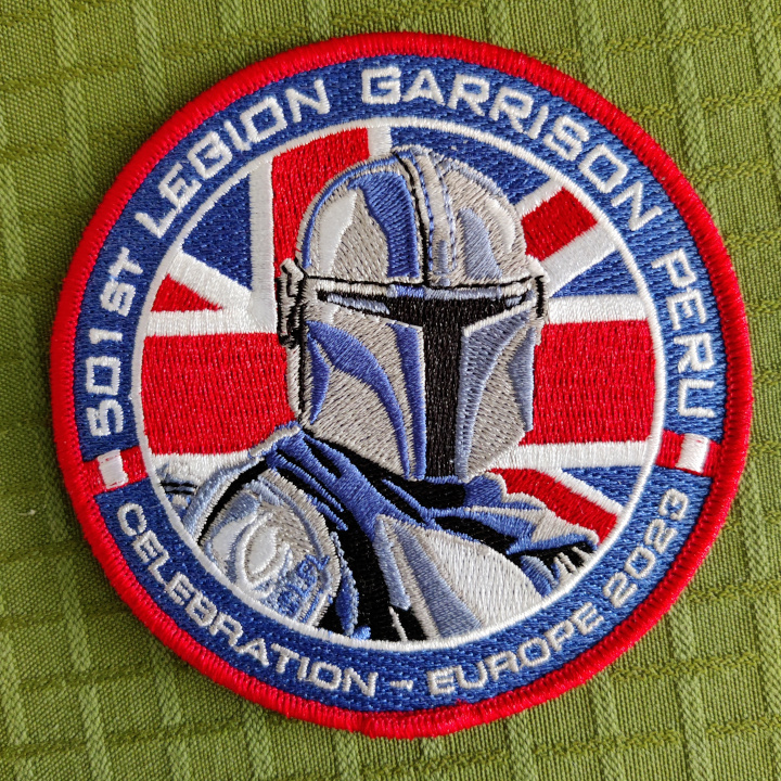 A round embroidered patch. Din Djarin is standing in front of the Union Jack. The text around the border reads: "501st Legion Garrison Peru" and "Celebration Europe 2023"