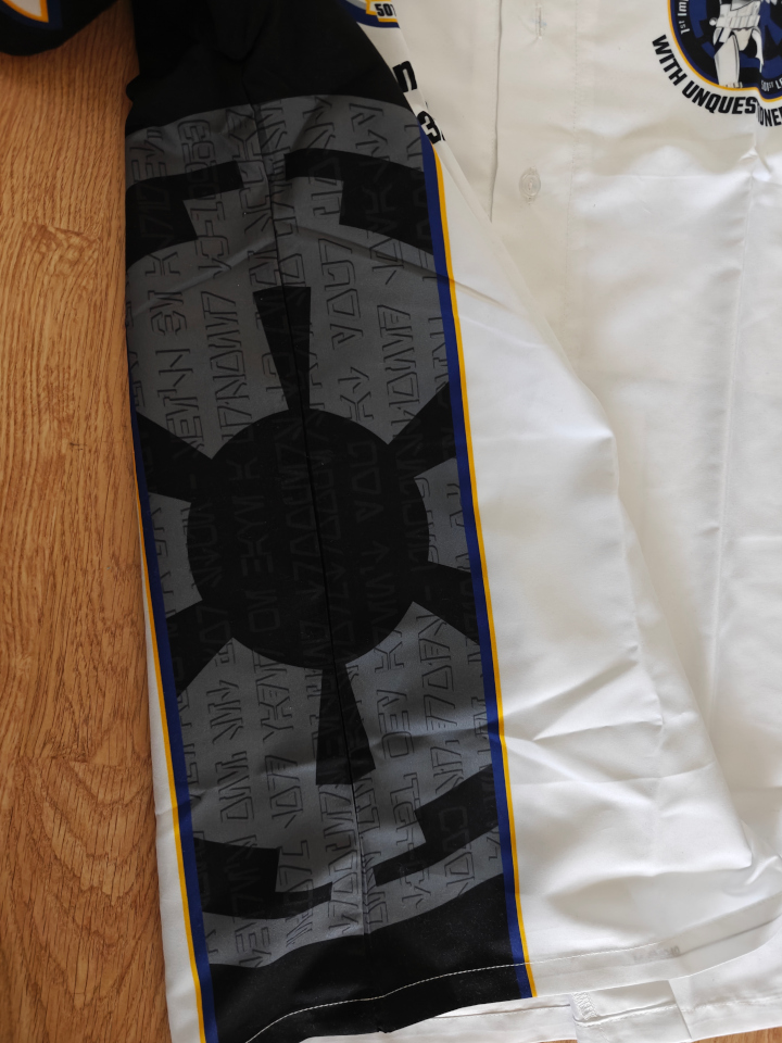 A close-up of the side of the shirt. We se that the symbols written on the cog is aurebesh letters.