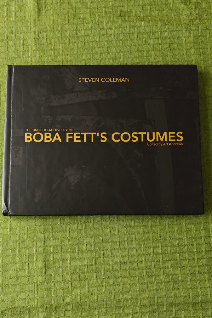 The front cover of the book. It is dark green, almost black, with a subtle dark green image of Boba Fett's helmet, almost not visible.