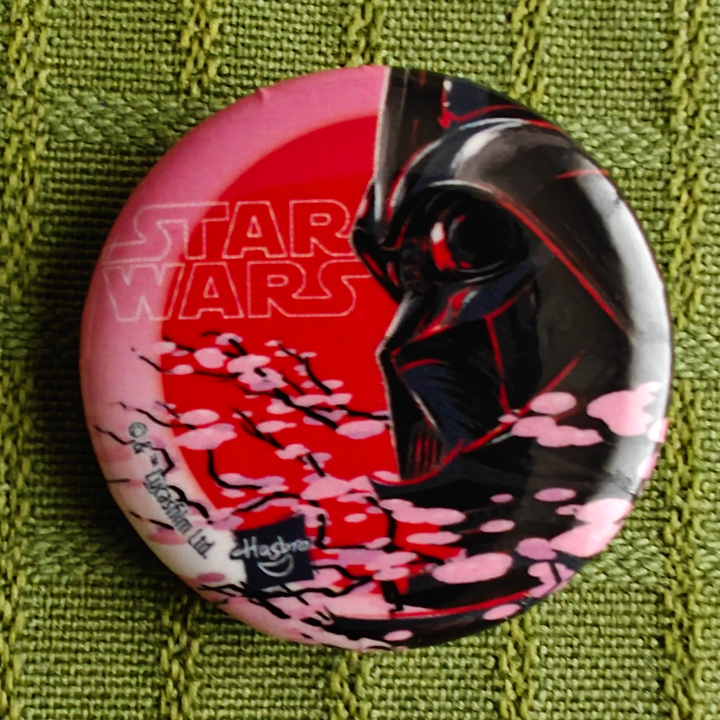 A button featuring Darth Vader with cherry blossoms and a red sun.