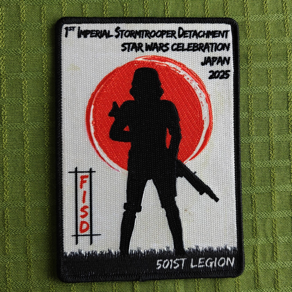 An embroidered patch featuring the silhouette of a stormtrooper in front of a red sun and a white background. Text: "1st Imperial Stormtrooper Detachment Star Wars Celebration Japan 2025", "FISD" and "501st Legion".