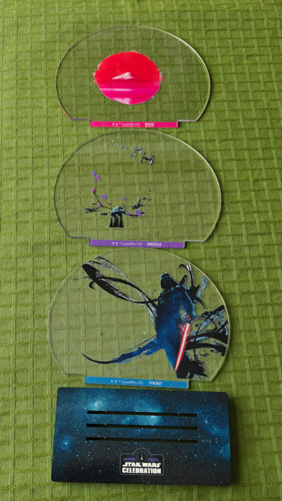 The sculpture disassembled to give a closer look at the discs. The front disc features Darth Vader in a dramatic pose. The middle disc features AT-AT, X-Wing, TIE Fighters and cherry blossoms branch. The back disc features a red circle with Mt. Fuji.