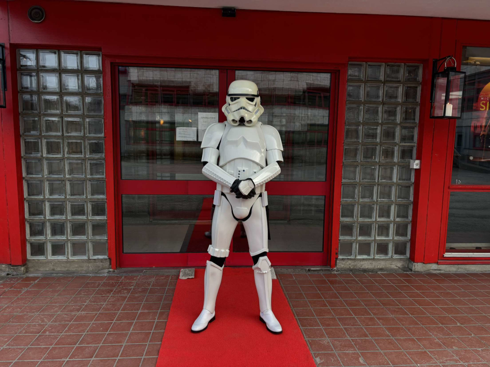 A stormtrooper stands guard on the red carpet in front of the theater.