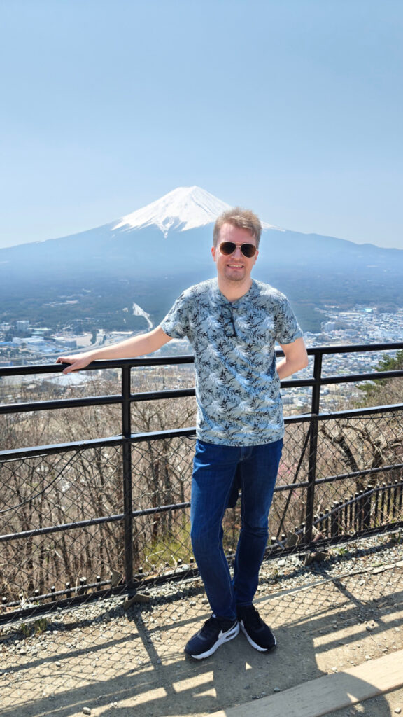 I am standing by a fence. Mt. Fuji is seen in the distance.